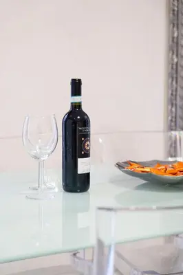 a glass table with a bottle of wine and a wine glass at Cipro Roomy House - Vatican in Rome
