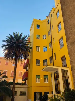 a yellow building with a palm tree in front of it at Antonioni's Apartment Trastevere in Rome