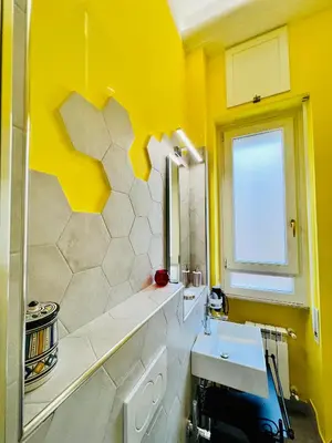 a yellow bathroom with a sink and a window at Antonioni's Apartment Trastevere in Rome