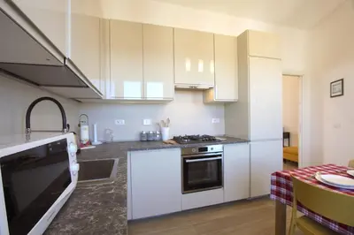 a kitchen with white cabinets and a stove top oven at Sunny Flaminio Terrace Penthouse in Rome