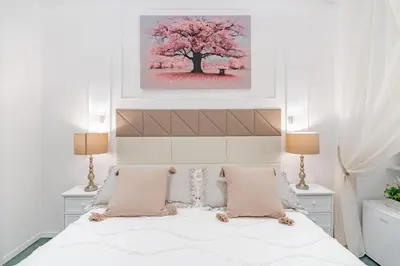 a bedroom with a large white bed with a tree at Glint House Roma Sapienza in Rome