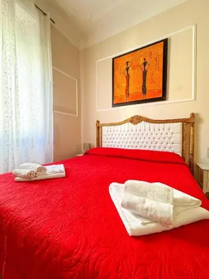 a bedroom with a red bed with two towels on it at Glint House Roma Sapienza in Rome