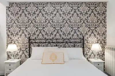 a bedroom with a white bed with a damask wallpaper at Glint House Roma Sapienza in Rome