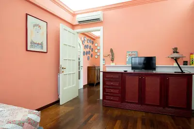 a bedroom with pink walls and a television on a dresser at La Terrazza di Paola San Giovanni in Rome