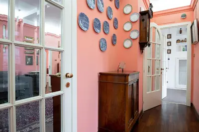a hallway with a pink wall with plates on the wall at La Terrazza di Paola San Giovanni in Rome