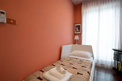 a bedroom with orange walls and a bed with towels on it at La Terrazza di Paola San Giovanni in Rome