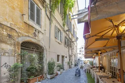 an alley in an old city with tables and plants at Farnese House in Rome