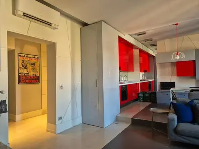 a living room and a kitchen with red cabinets at Attico Cavour Prati, vicino Piazza Navona, Castel Sant'Angelo e San Pietro in Rome