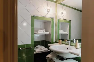 a green and white bathroom with a sink and mirror at Artemide Domus Romae in Rome