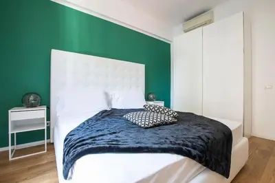 a bedroom with a white bed with a green wall at My Trastevere Three Bedroom View Apartment in Rome