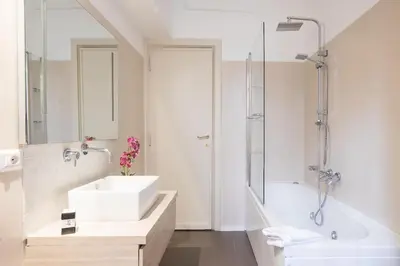 a white bathroom with a sink and a tub at My Trastevere Three Bedroom View Apartment in Rome