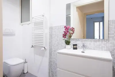 a bathroom with a sink and a toilet and a mirror at My Trastevere Three Bedroom View Apartment in Rome