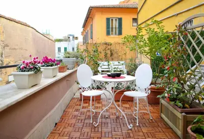 a patio with a table and chairs on a balcony at Terrace Modern Studio Trastevere in Rome