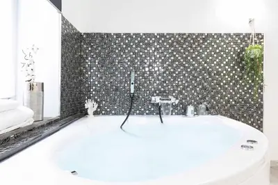 a white bath tub in a bathroom with a tile wall at Trastevere Silver King Jacuzzi Suite in Rome