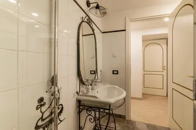 a white bathroom with a sink and a mirror at GuestHost - Palazzo Altieri Elegant Apartment in Rome