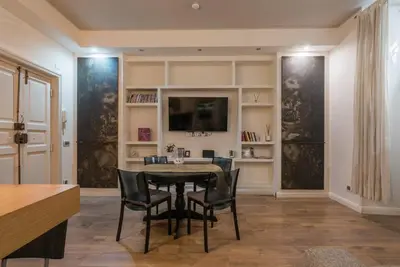 a dining room with a table and chairs and a television at La luna nel pozzo a Roma in Rome