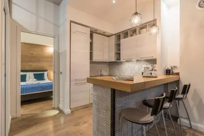a kitchen with white cabinets and a bar with stools at La luna nel pozzo a Roma in Rome