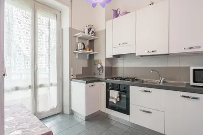 a kitchen with white cabinets and a sink and a window at Charming Mazzini Apartment in Rome