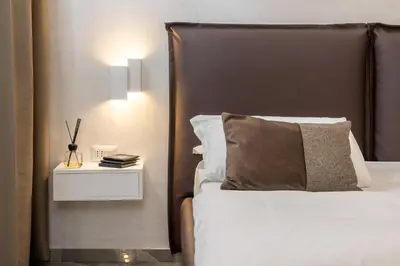 a bed with a brown headboard and a nightstand with a bed sidx sidx at DolceVitaSuite in Rome