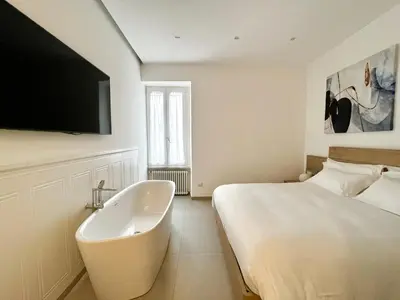 a white bedroom with a bed and a bath tub at TRASTEVERE URBAN SUITE in Rome