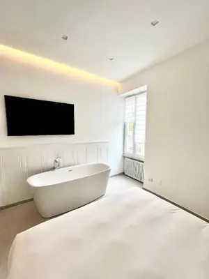 a white bathroom with a tub and a flat screen tv at TRASTEVERE URBAN SUITE in Rome