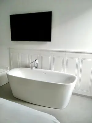 a white tub in a room with a tv on the wall at TRASTEVERE URBAN SUITE in Rome