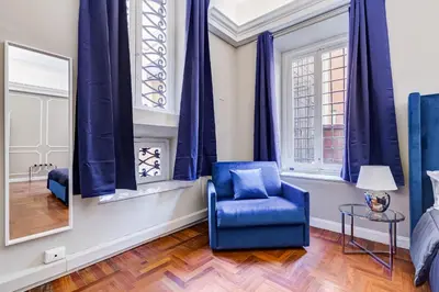 a blue chair in a room with windows at SPANISH GARDEN in Rome
