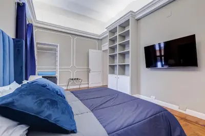 a bedroom with a bed with blue pillows and a flat screen tv at SPANISH GARDEN in Rome