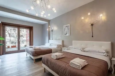 a bedroom with two beds and a chandelier at Naima Apartment San Pietro in Rome