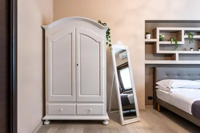 a bedroom with a white cabinet next to a bed at Naima Apartment San Pietro in Rome