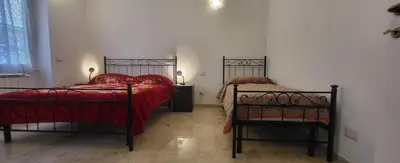 a bedroom with two beds with red sheets and a chair at Apartment Nonna Anna in Rome