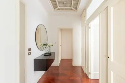 a hallway with a mirror and a table with flowers at iFlat Veneto Area's Penthouse in Rome