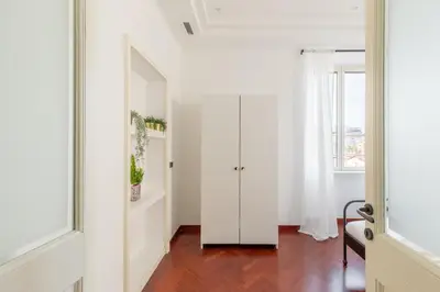 a hallway with white walls and a door with a mirror at iFlat Veneto Area's Penthouse in Rome