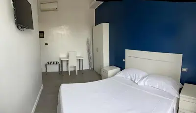 a bedroom with a white bed and a blue wall at Boutique Rooms in Rome