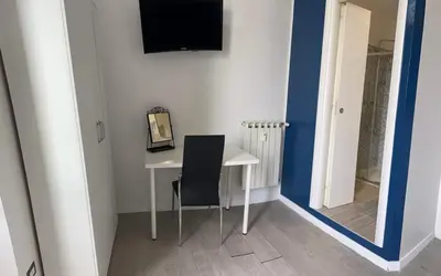 a white table with a chair and a television on a wall at Boutique Rooms in Rome