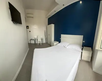 a bedroom with a large white bed with a blue wall at Boutique Rooms in Rome