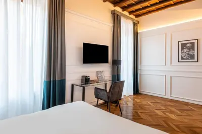a bedroom with a bed and a desk with a television at Largo Arenula Suites in Rome