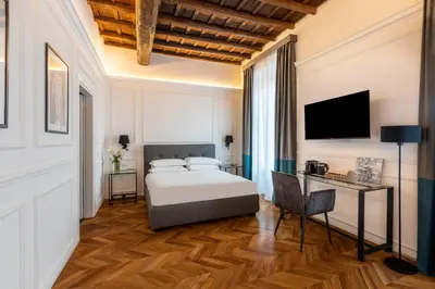 a bedroom with a bed and a desk and a television at Largo Arenula Suites in Rome