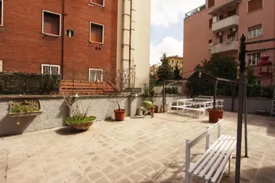 a patio with a bench and a table and buildings at Angelo Emo Flat in Rome