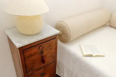 a lamp on a dresser next to a bed with a book at Vatican Charme in Rome