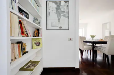 a dining room with a white wall with bookshelves at Vatican Charme in Rome