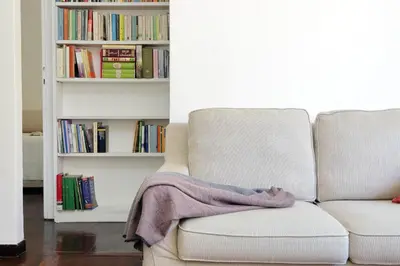 a couch with a blanket on it next to a book shelf at Vatican Charme in Rome
