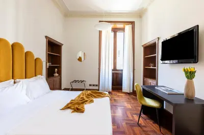 a bedroom with a bed and a desk and a television at DEZA Case vacanza Nazionale Joy e Living in Rome