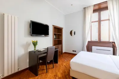 a hotel room with a bed and a desk and a tv at DEZA Case vacanza Nazionale Joy e Living in Rome
