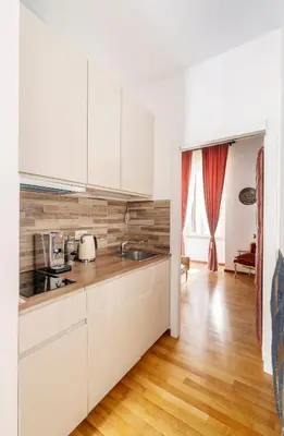 a kitchen with white cabinets and a wooden floor at Pantheon Caravaggio's House in Rome