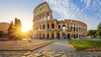 a large building with the sun setting behind it at ETERNA Trastevere Apartment in Rome