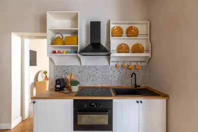 a kitchen with white cabinets and a sink and shelves at iFlat Lovely Flat in Trastevere in Rome