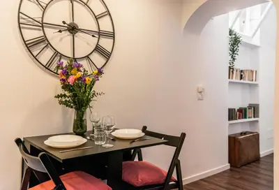 a dining room with a table with a large clock on the wall at Piacentino Homes Corso apartment in Rome