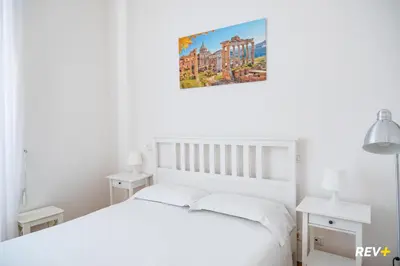 a bedroom with a white bed and a painting on the wall at Mecenate Apartment Colosseum in Rome