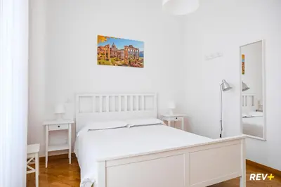 a white bedroom with a white bed and a painting on the wall at Mecenate Apartment Colosseum in Rome